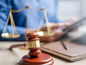 gavel sitting in front of scales of justice and notebook and pen